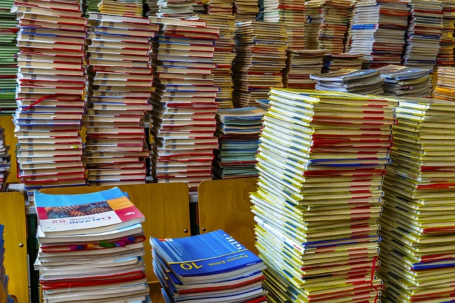 Stapelweise Bücher auf Tischen und Stühlen.