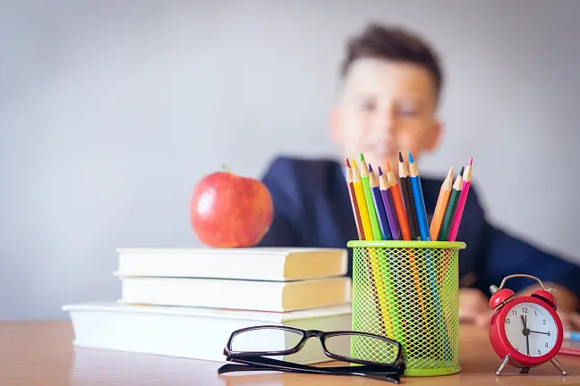 Ein Junge sitzt am Schreibtisch mit Büchern und Stiften.